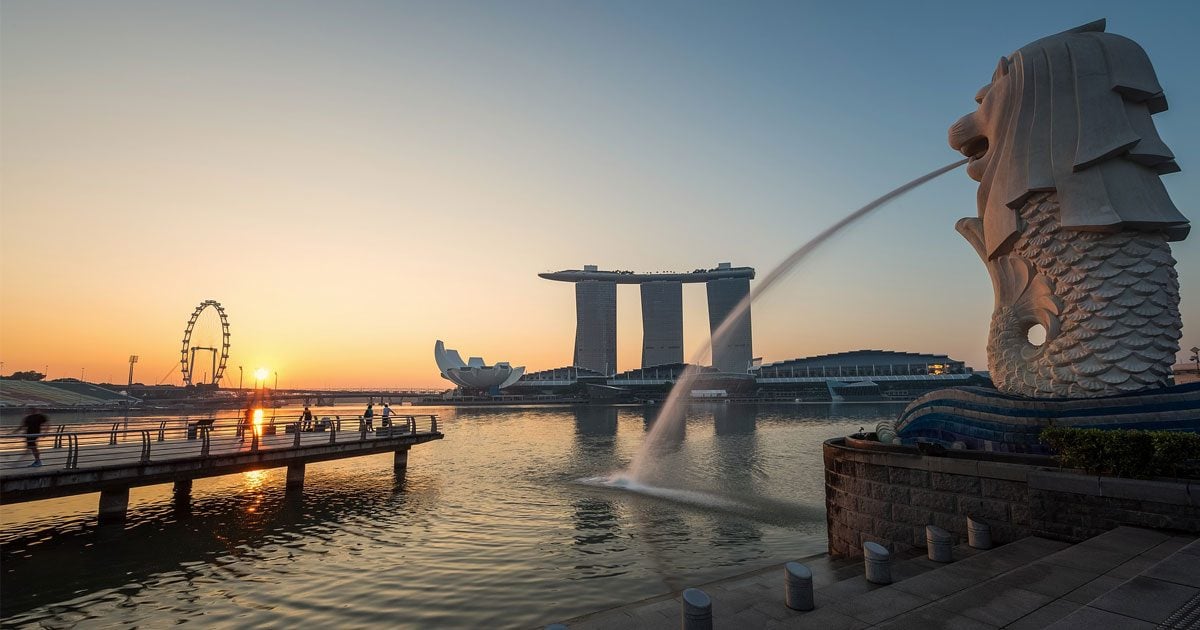 The sun rises over a peaceful day in Singapore, beside the famous merlion.