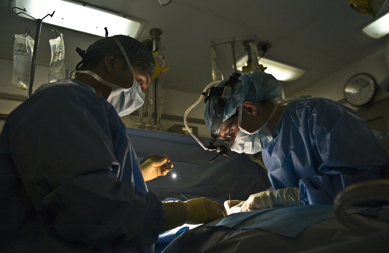 Surgeons lean over a patient on the operating table.