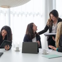 A group of women in black blazer having conversation inside the office.