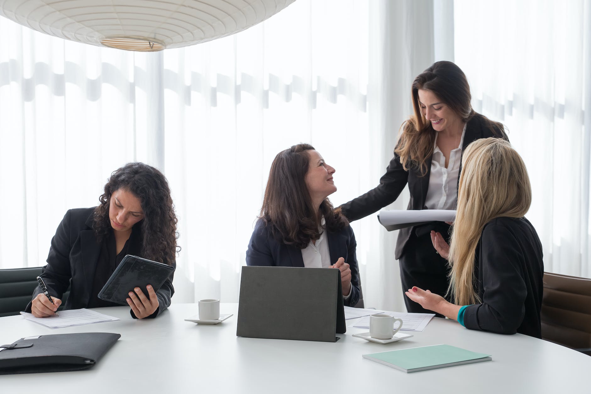 A group of women in black blazer having conversation inside the office.