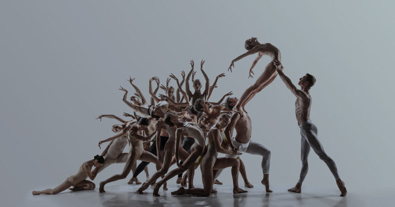 A team of dancers in the middle of their choreography with a single dancer flying out of the mass of bodies.