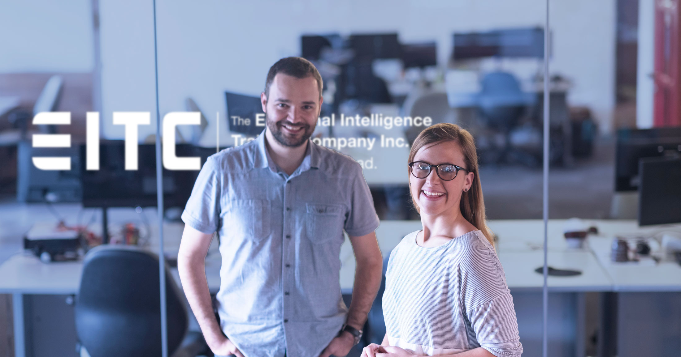 Two EITC alumni stand in their office laughing, with the EITC logo hovering in the background.